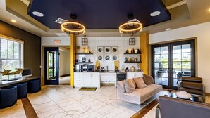 A spacious living area with a sofa, a coffee table, and a TV. There is a kitchen area with a sink, stove, and cabinets. The room has a tiled floor and a ceiling with recessed lighting. - Fort Myers 1BR Condo | Pool + Gym + BBQ (Fort Myers)