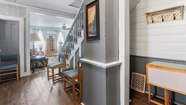 A hallway with a staircase, wooden chairs, a table, and a decorative wall piece. - Pet-Friendly Historic 4BR Home in Illinois (Lynn Center)