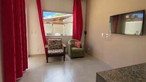 A living room with a ceiling fan, a TV mounted on the wall, and two chairs. - A very cozy house for couples! (Cabo Frio)