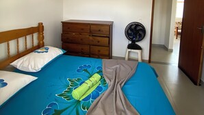 A bedroom with a bed, a wooden dresser, a ceiling fan, and a fan on a small table. - A very cozy house for couples! (Cabo Frio)