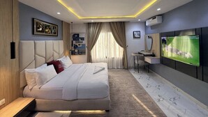 A modern hotel room with a large bed, a desk, a TV, and a bathroom. - Spacious 3-bedroom apartment in Victoria Island - VI, Lagos (Lagos)