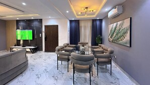 A modern living room with a round glass table, a sofa, a TV, and a painting on the wall. - Spacious 3-bedroom apartment in Victoria Island - VI, Lagos (Lagos)