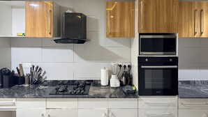 A modern kitchen with wooden cabinets, a double oven, and a gas stove. - Spacious 3-bedroom apartment in Victoria Island - VI, Lagos (Lagos)