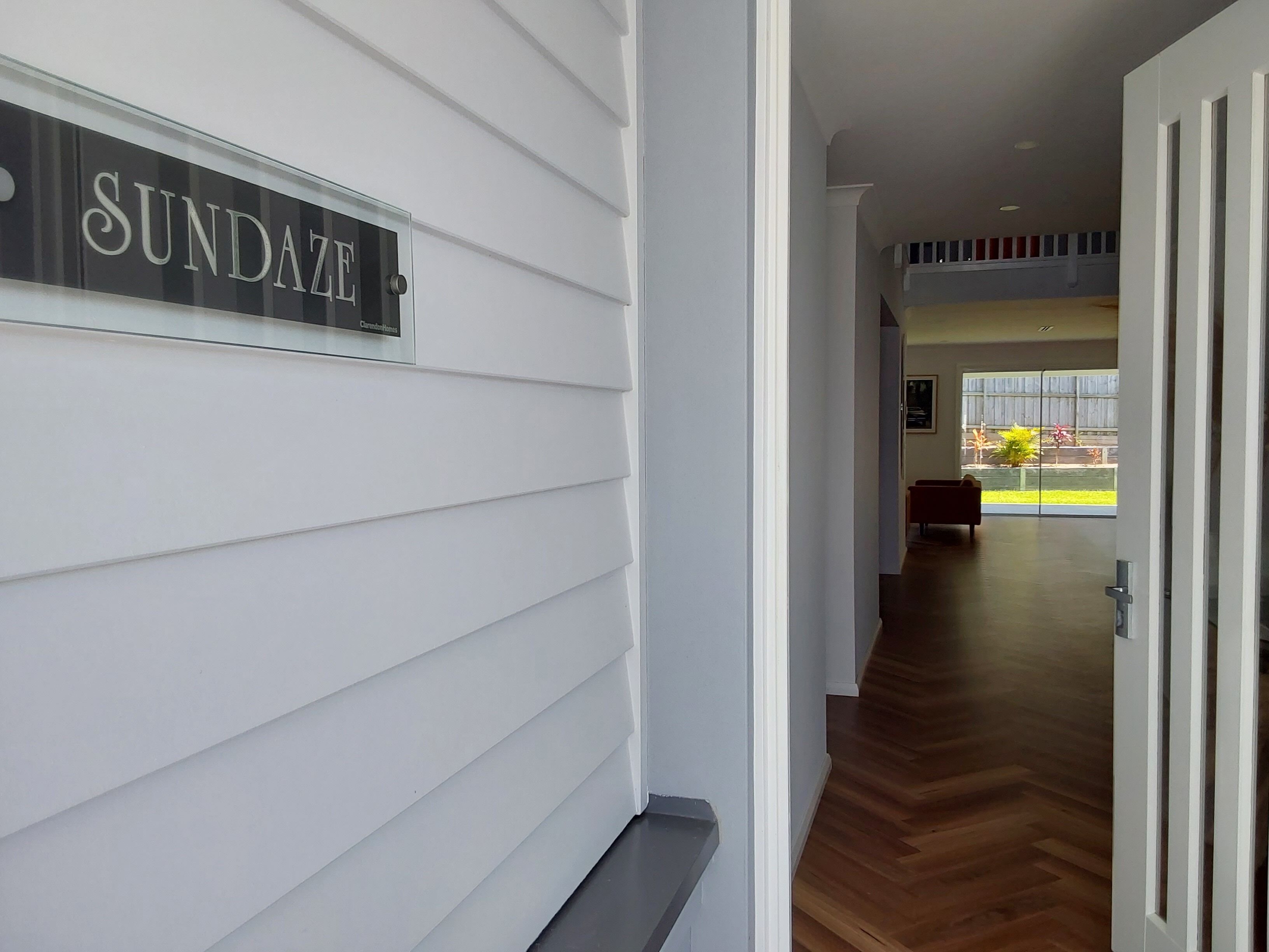 A hallway with a sign reading "SUNDANCE" on the wall, leading to a room with a large window and a bench.