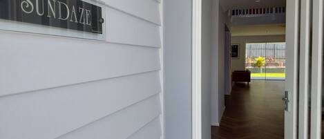 A hallway with a sign reading "SUNDANCE" on the wall, leading to a room with a large window and a bench.