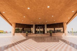 A spacious entrance with a checkered floor, a covered area with columns, and a clear view of the building's entrance. - Aram Hotel - AlMeshael Exit 18 (Riyadh)