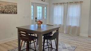 A dining area with a wooden table, two chairs, a hexagonal light fixture, and a patterned rug. - Modern & open 3-bedroom house with 3 stall garage in a perfect location.. (Ventura)