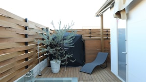 A rooftop deck with a hot tub, a potted plant, and a sun lounger. - Villa with a Natural Spring Bath and Wood-Fired Sauna — Aoshima (宮崎市青島)