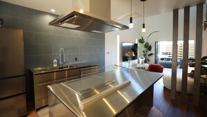 A modern kitchen with stainless steel appliances, a central island, and a large window providing natural light. - Villa with a Natural Spring Bath and Wood-Fired Sauna — Aoshima (宮崎市青島)