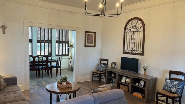 A living room with a sofa, a television, and a dining area with a table and chairs.