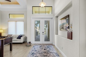 A spacious living area with a pool table, a sofa, and a large window. - NEW LISTING: Relaxing Escape! Waterfront Heated Pool Oasis (Cape Coral)