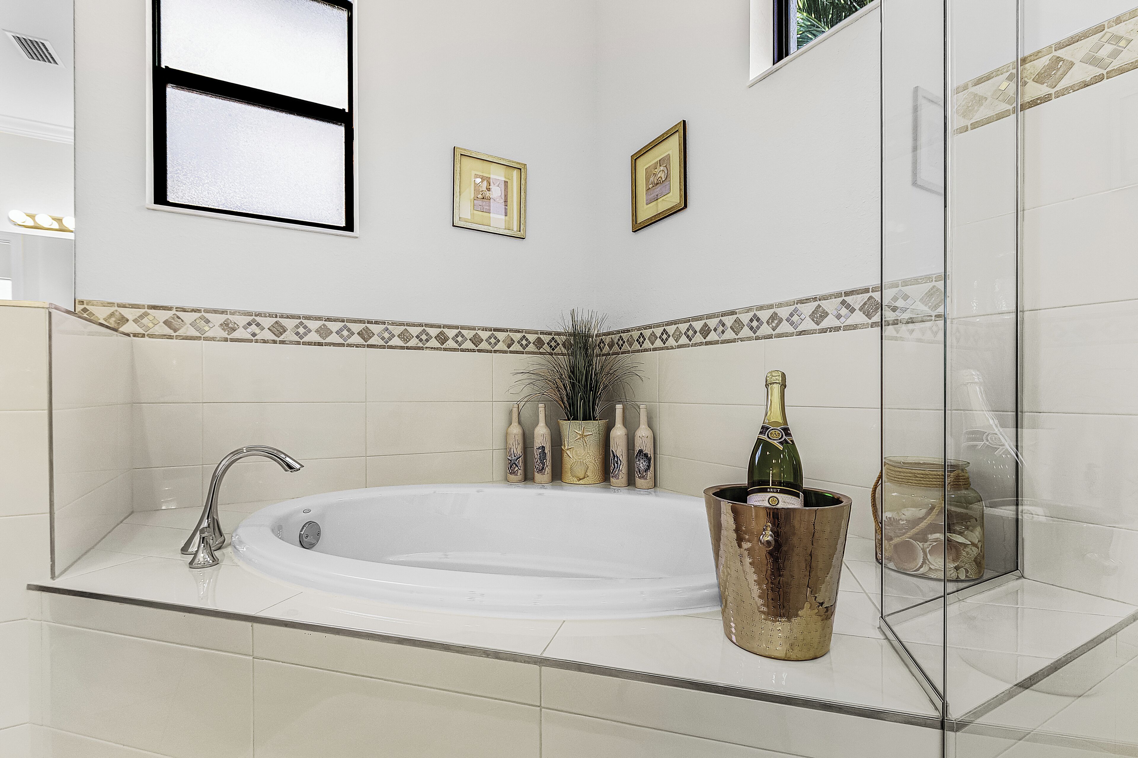 A modern bathroom with a freestanding bathtub, a glass shower enclosure, and decorative bottles and a jar on the counter.