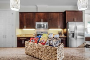 A kitchen with a woven basket containing snacks and water bottles on the counter. - NEW LISTING: Relaxing Escape! Waterfront Heated Pool Oasis (Cape Coral)