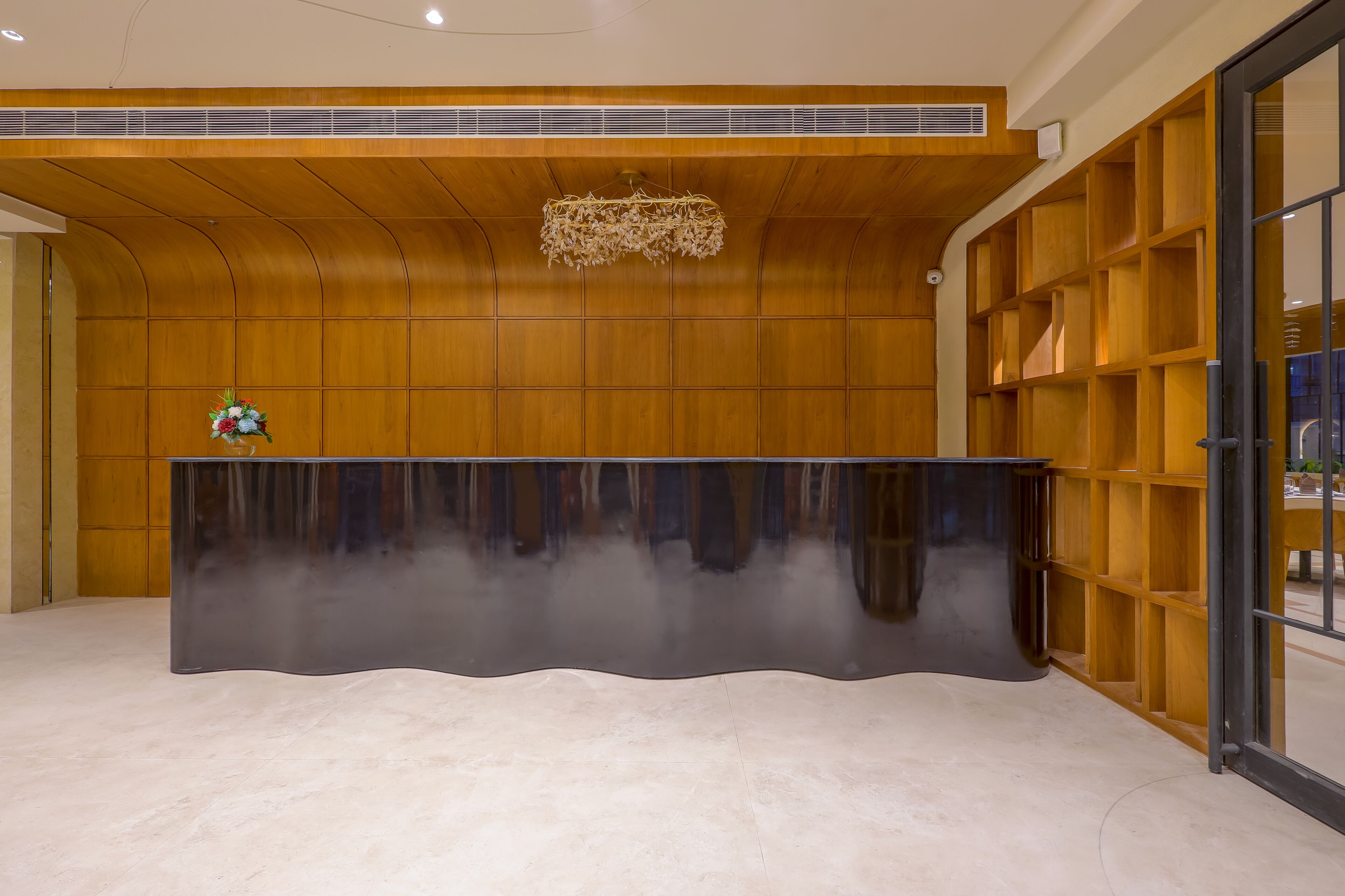A reception area with a curved black reception desk, wooden panel walls, and a large window on the right.