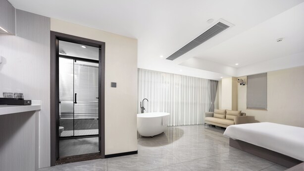 Ein modernes Hotelzimmer mit einer Badewanne, einem Sofa und einem großen Bett.