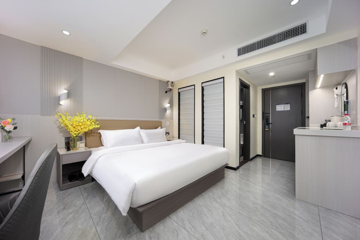 Una habitació d'hotel moderna amb un llit gran, un escriptori i una tocador amb mirall.