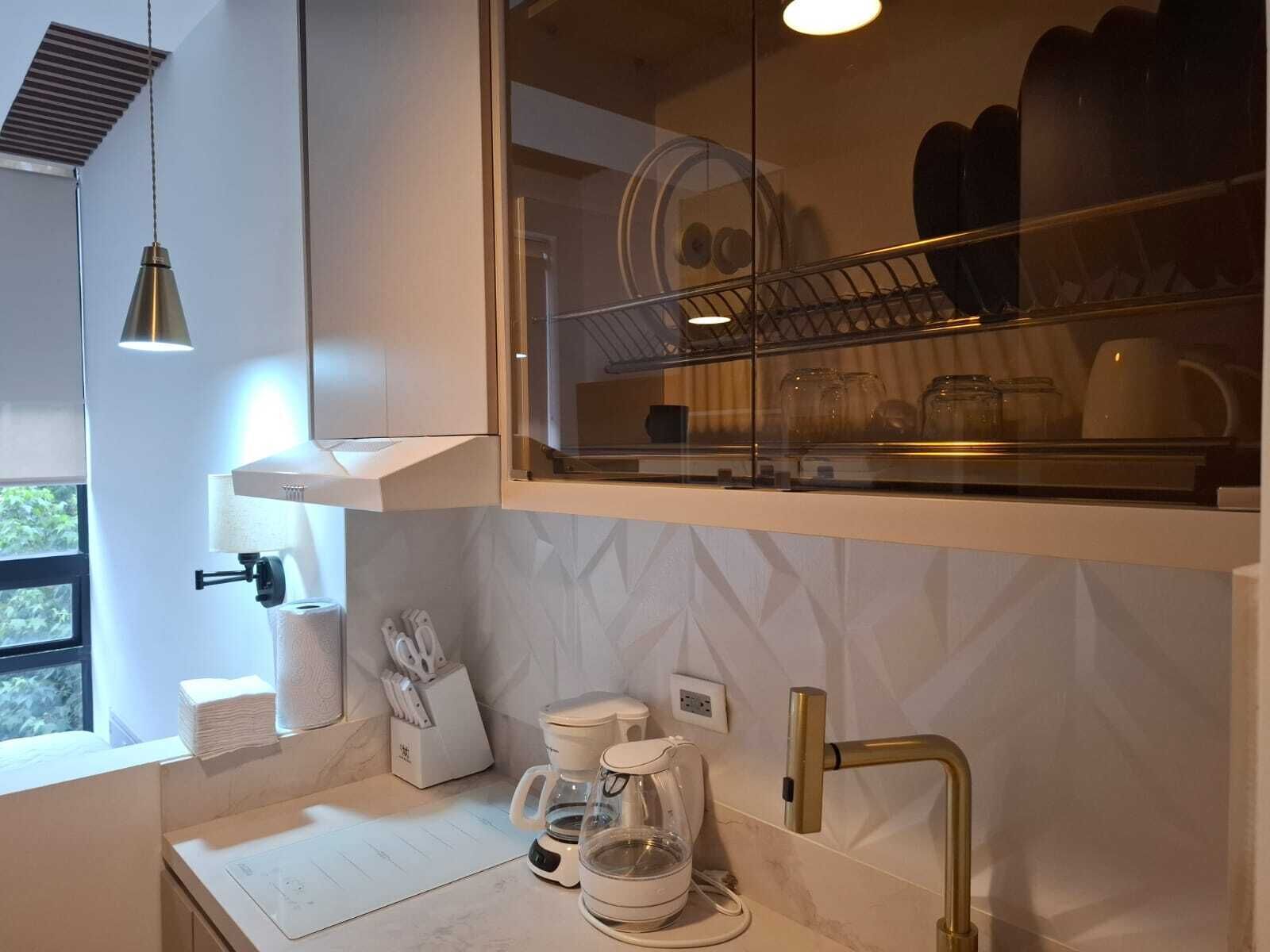 A modern kitchen with a built-in dishwasher, a coffee maker, and a glass coffee pot on the counter.