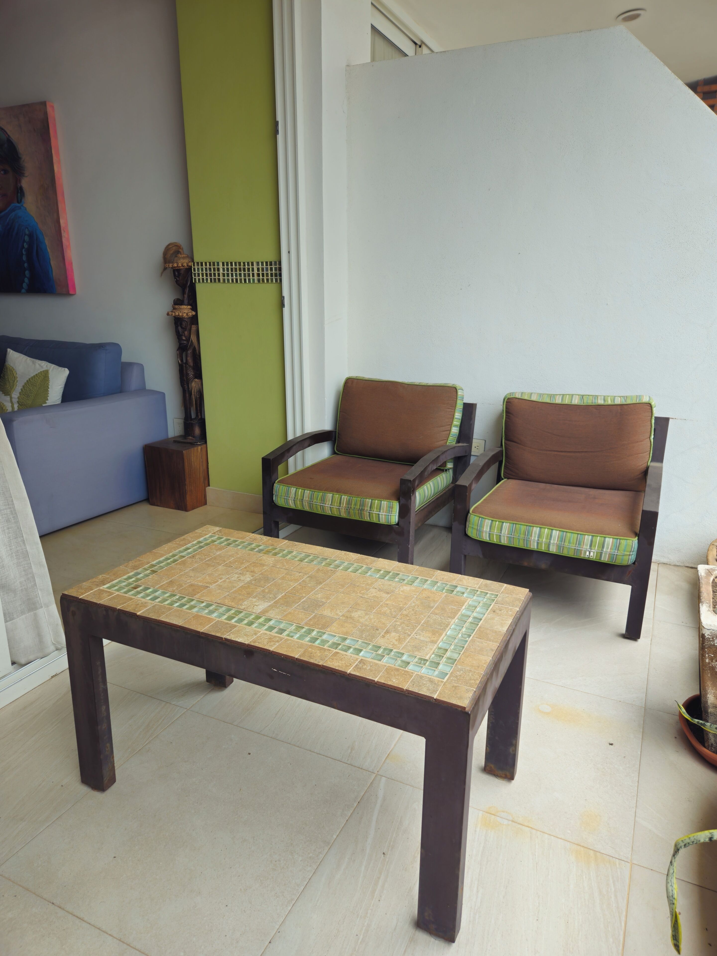 Una sala de estar con un sofá, dos sillones, una mesa de centro y una escultura decorativa.