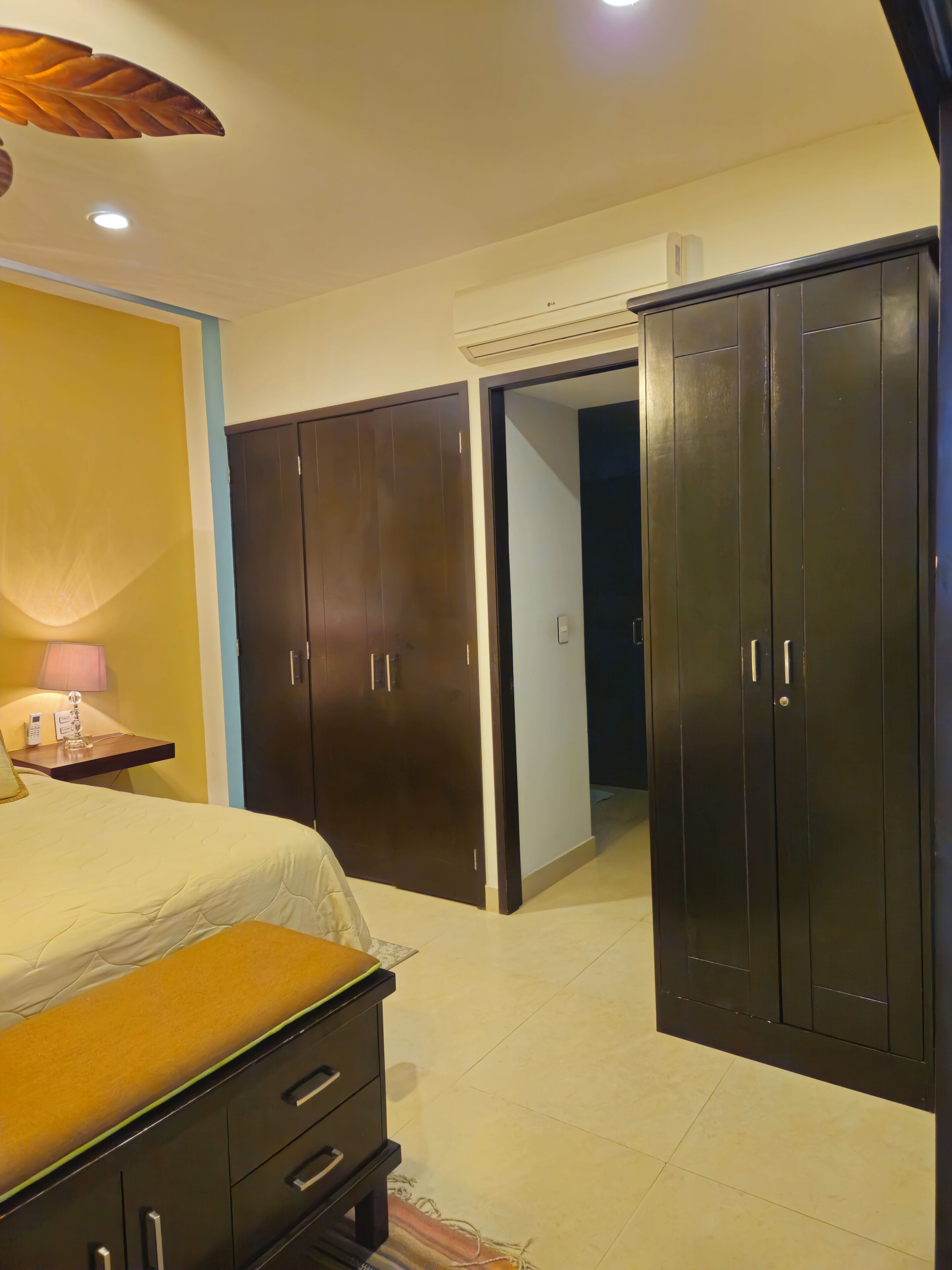 A bedroom with a bed, a nightstand, a lamp, and a wardrobe.