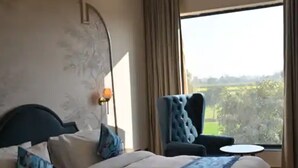 A modern hotel room with a large bed, a chair, a small table, and a view of the outdoors. - Hotel Phantom (Ganganagar)