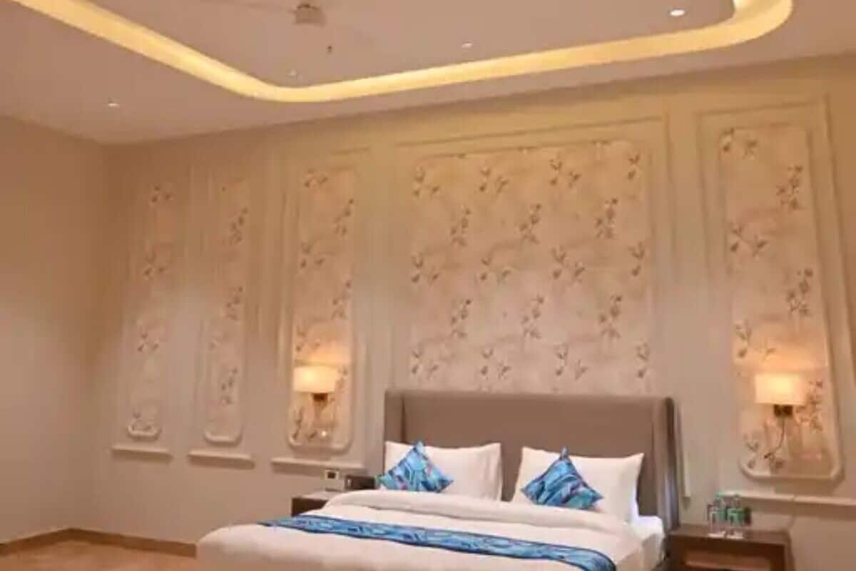 A modern bedroom with a large bed, recessed ceiling lighting, and decorative wall panels.