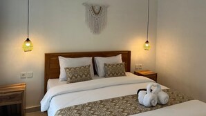 Een net opgemaakt bed met gestreepte kussens, een macramé wanddecoratie en twee hanglampen.
