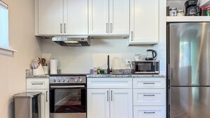 Eine moderne Küche mit weißen Schränken, Edelstahlgeräten und einem eingebauten Backofen.