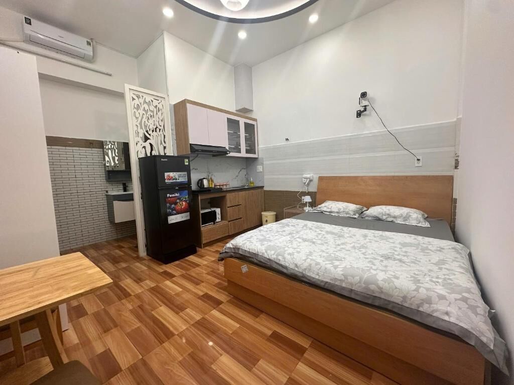 Une pièce de taille modeste comprenant un lit, une petite table, un coin cuisine et un panneau décoratif mural.
