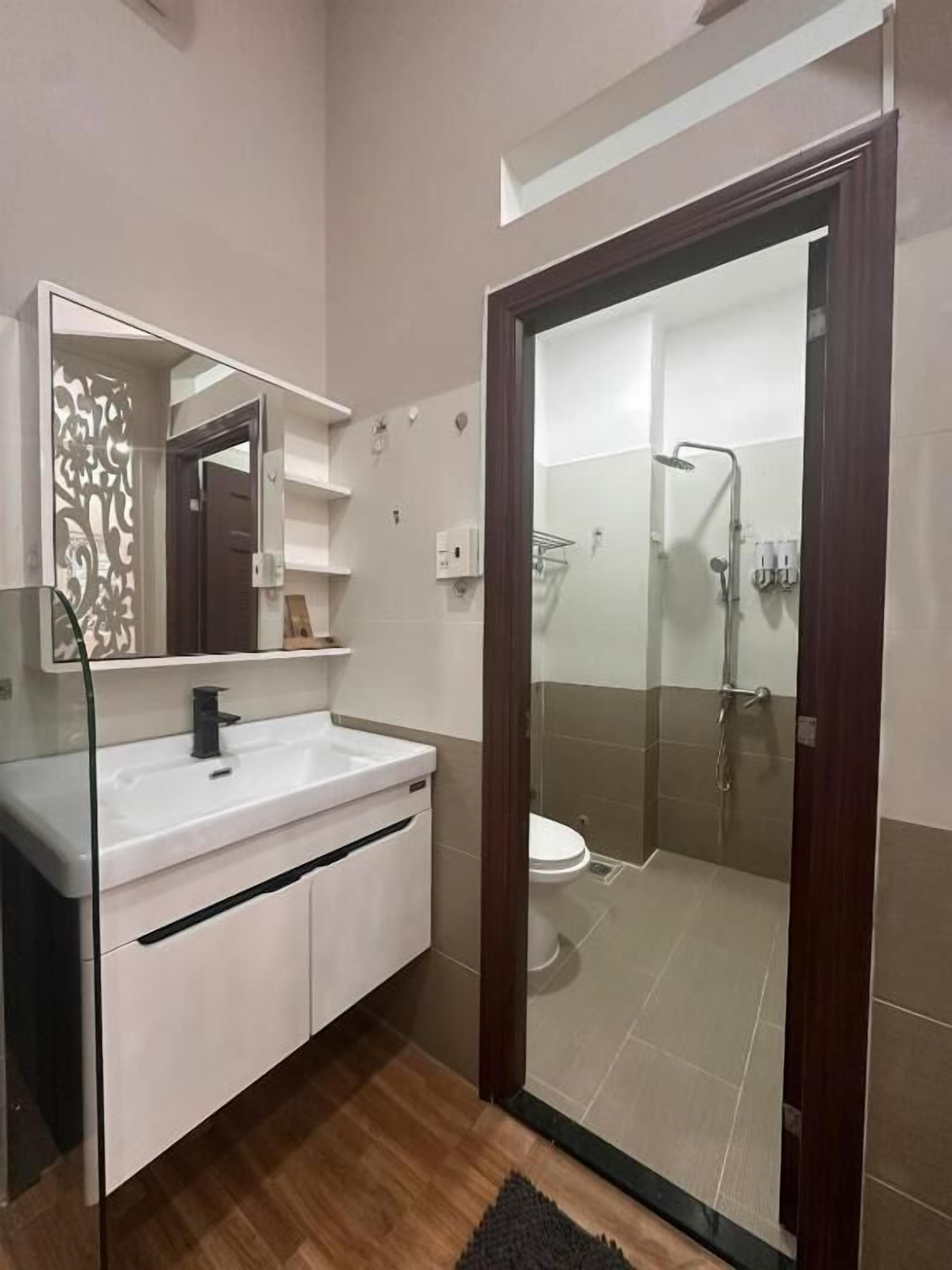 A modern bathroom with a white vanity, a glass shower enclosure, and a wooden floor.