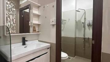 A modern bathroom with a white vanity, a glass shower enclosure, and a wooden floor.