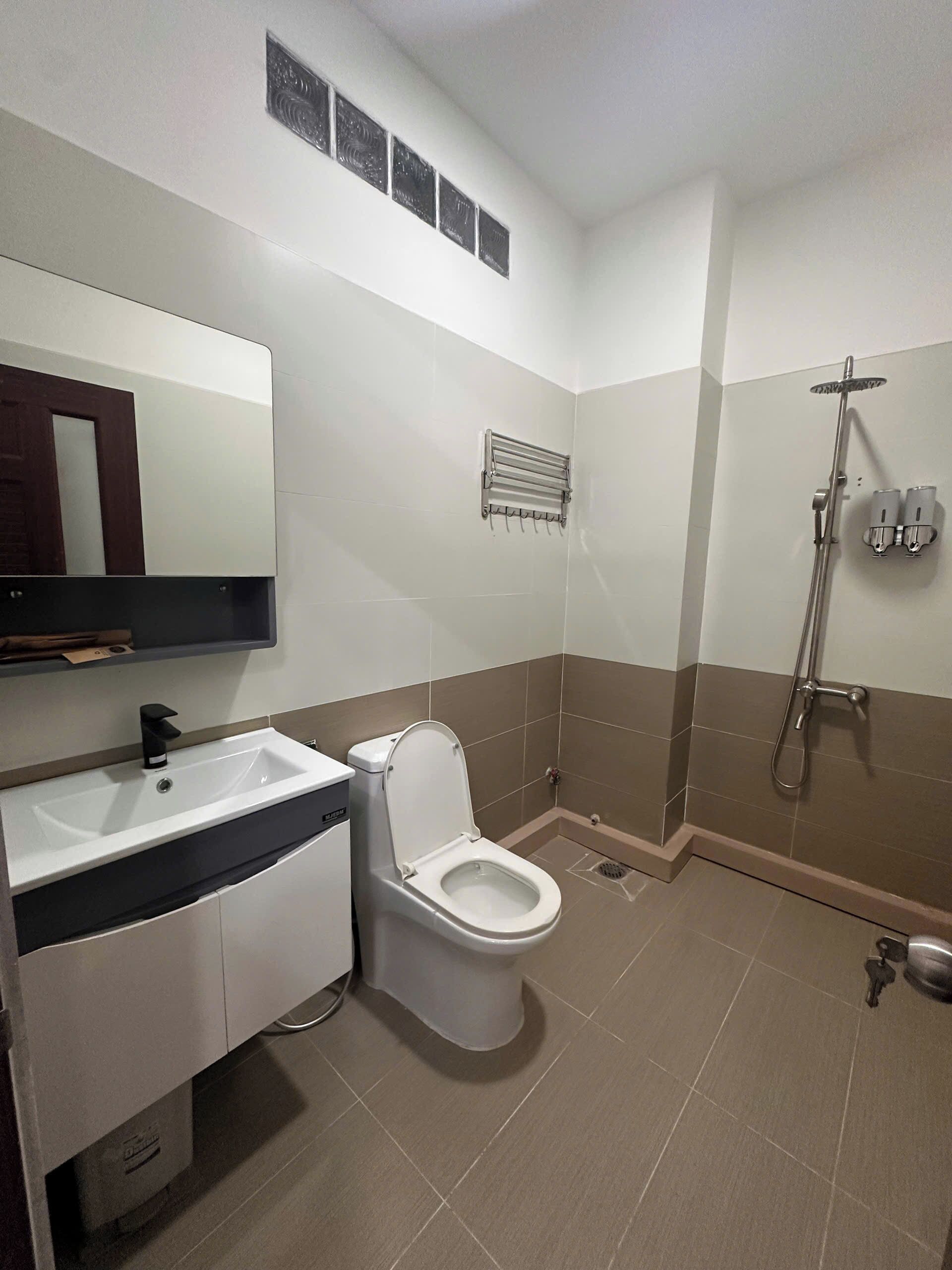 Une salle de bain moderne avec un lavabo blanc, des toilettes et un espace douche.