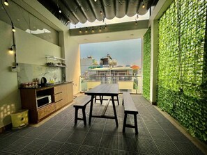 A modern kitchen with a dining area, a green wall, and a view of buildings. - AP Home (Ho Chi Minh City)