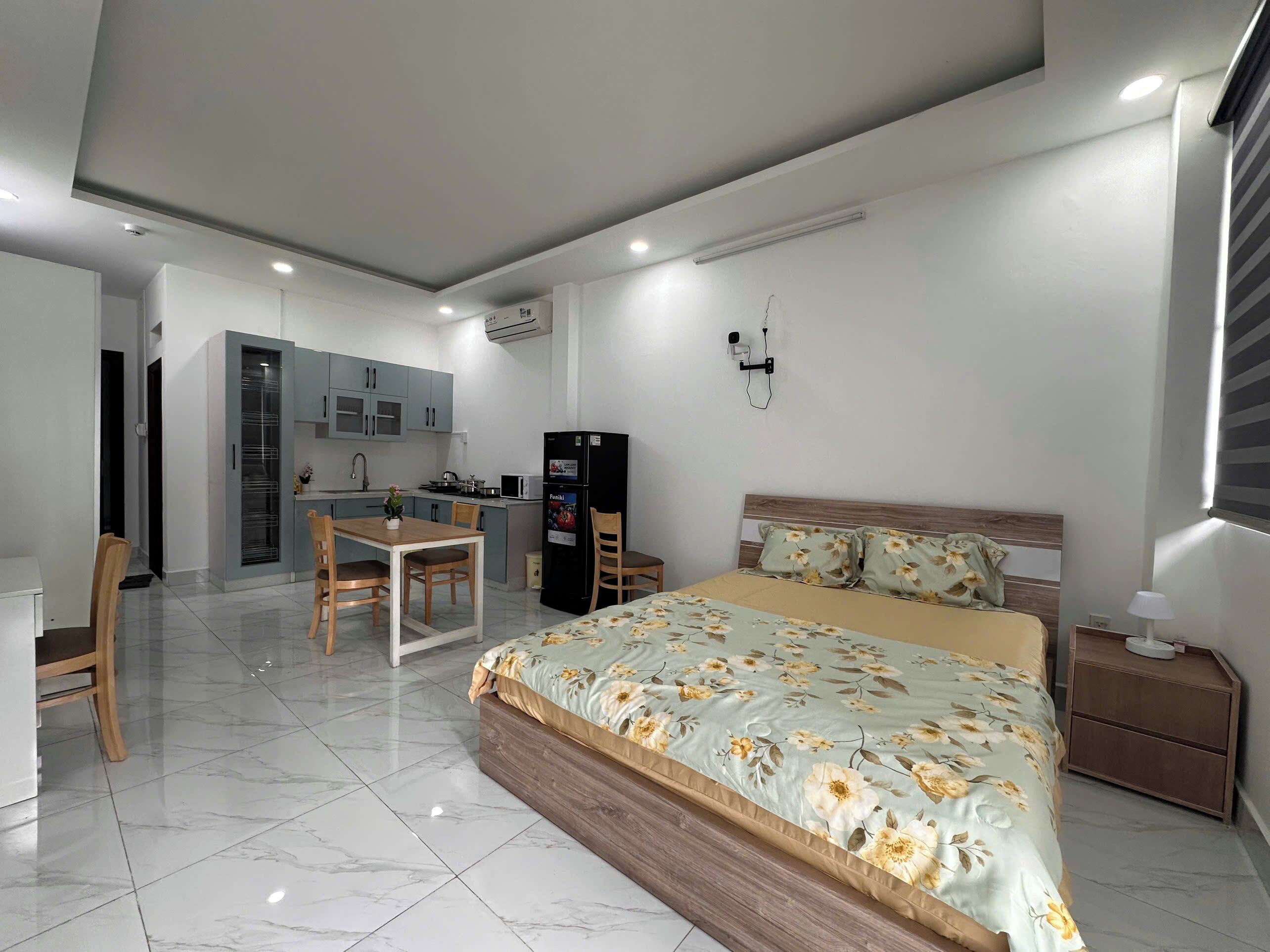Un dormitorio moderno con una cama grande, una mesita de noche de madera y una pequeña zona de escritorio con una silla.