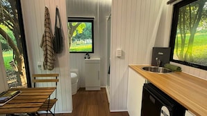 A compact kitchen with wooden flooring, a built-in sink, and a window overlooking greenery. - Under the Velvet Sky by Tiny Away (Dagun)