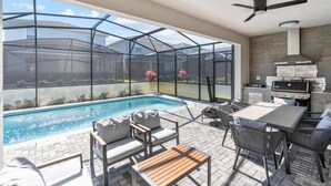 A modern outdoor patio with a pool, seating, and a grill area. - 5BR 5BA Luxury Villa Private Pool Resort - WCA (Clermont)