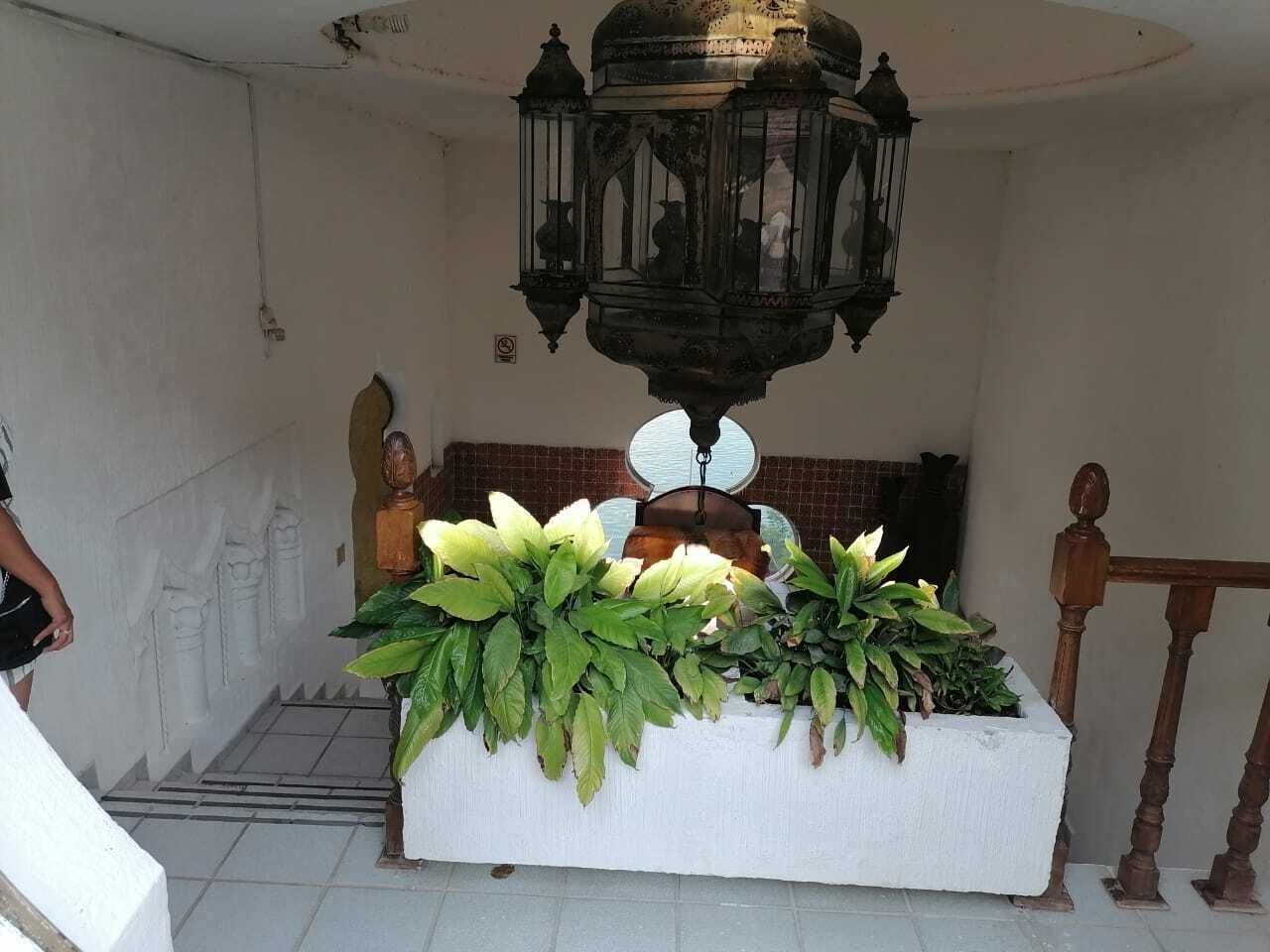 A room with a white altar, a hanging lantern, and a potted plant arrangement.
