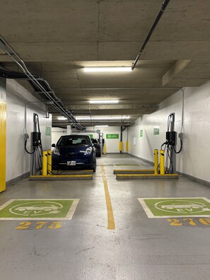 An underground parking garage with EV charging stations, marked parking spaces, and clear signage. - Amazing Views, Close to Football Stadium, Cruiseliners (Vancouver)