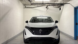 A white car parked in a parking garage with white brick walls and a blue door. - Amazing Views, Close to Football Stadium, Cruiseliners (Vancouver)