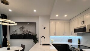 A modern kitchen with a marble island, stainless steel appliances, and a dining area with a chandelier. - Amazing Views, Close to Football Stadium, Cruiseliners (Vancouver)