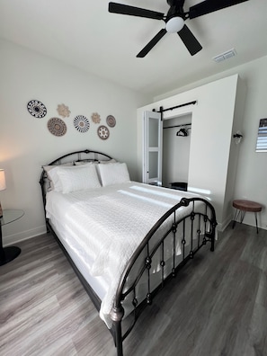 Un dormitorio con una cama, un ventilador de techo, una mesita de noche y una pared decorada con platos.