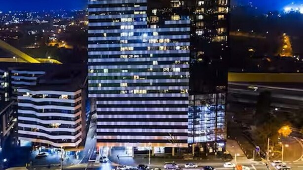 Ein Hochhaus mit mehreren Stockwerken und beleuchteten Fenstern bei Nacht.