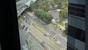Blick von einem Hochhaus auf eine Stadtlandschaft mit einer gewundenen Hochstraße, mehreren Fahrspuren und umliegender Vegetation.