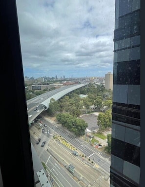 Blick von einem Hochhaus auf eine Stadtlandschaft mit einer gewundenen Hochstraße, mehreren Fahrspuren und umliegender Vegetation.