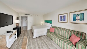 Une chambre d’hôtel avec un lit, un canapé, une télévision, un bureau et une chaise.