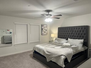 Ein Schlafzimmer mit einem großen Bett, einem Deckenventilator und einem Fenster mit Jalousien.
