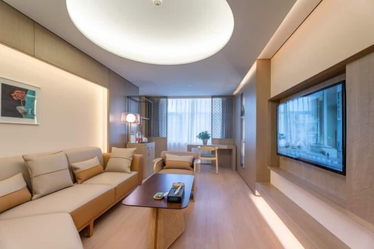 Ein modernes Hotelzimmer mit Sofa, Couchtisch, Schreibtisch und Fernseher.