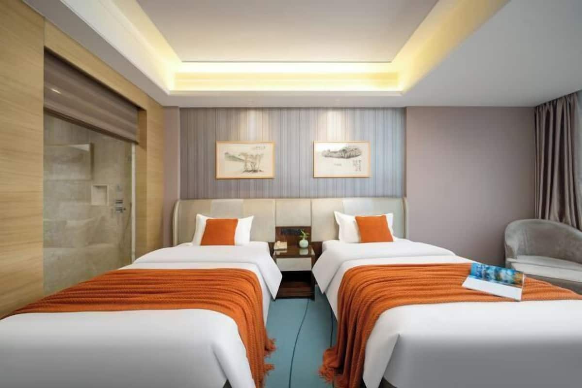 Ein Hotelzimmer mit zwei Betten, einem Nachttisch, einem Stuhl und Bildern an der Wand.