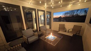 Un patio exterior con mobiliario, una chimenea y vistas al atardecer.