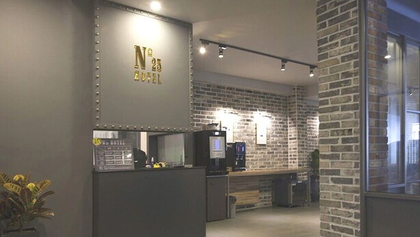 Un espace d’accueil au design moderne, comprenant un comptoir de réception, une machine à café et un mur en briques.
