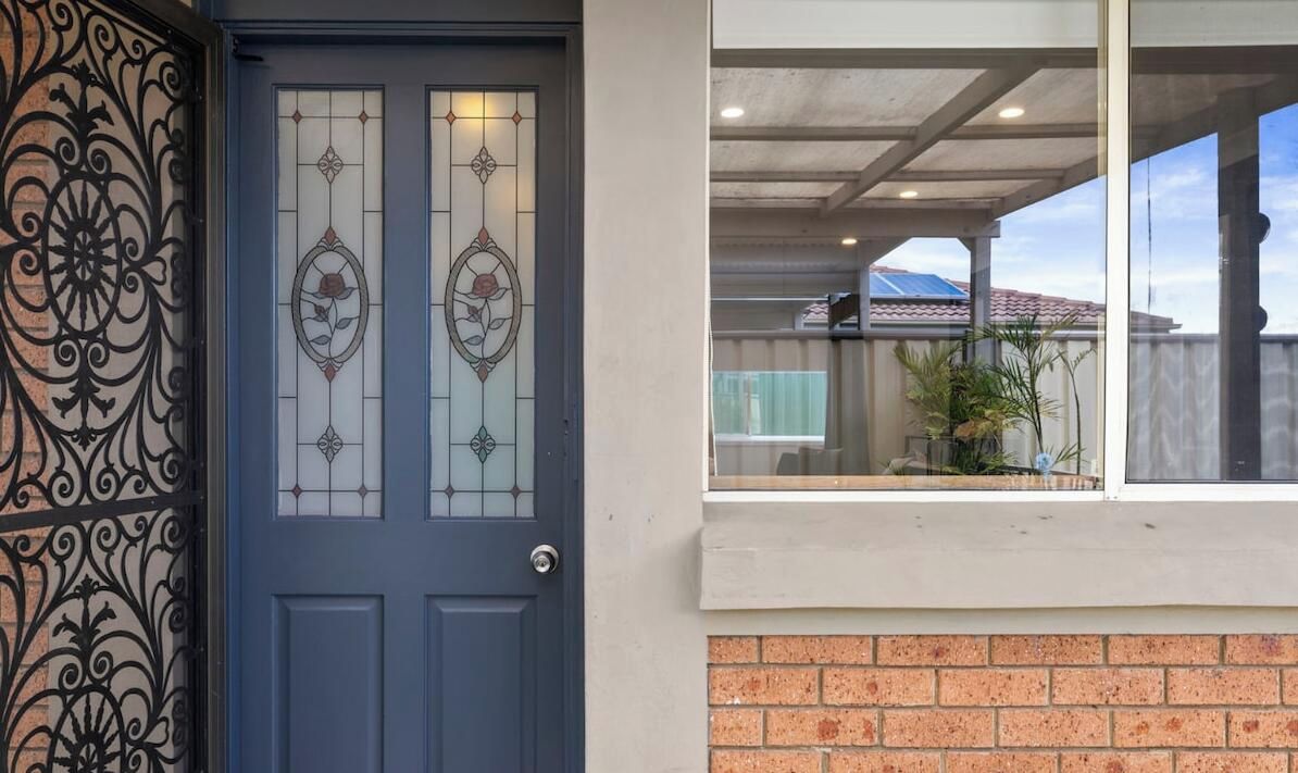 A blue door with decorative glass panels and a wrought iron gate.
